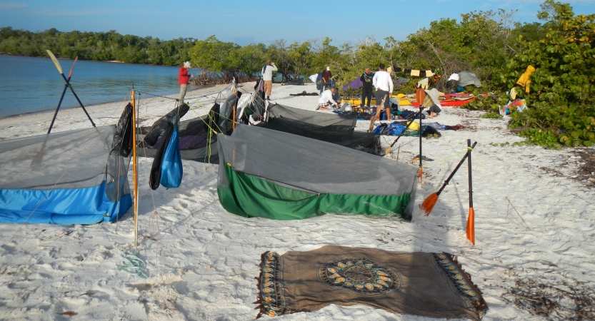 a collection of shelters rest on a sandy beach